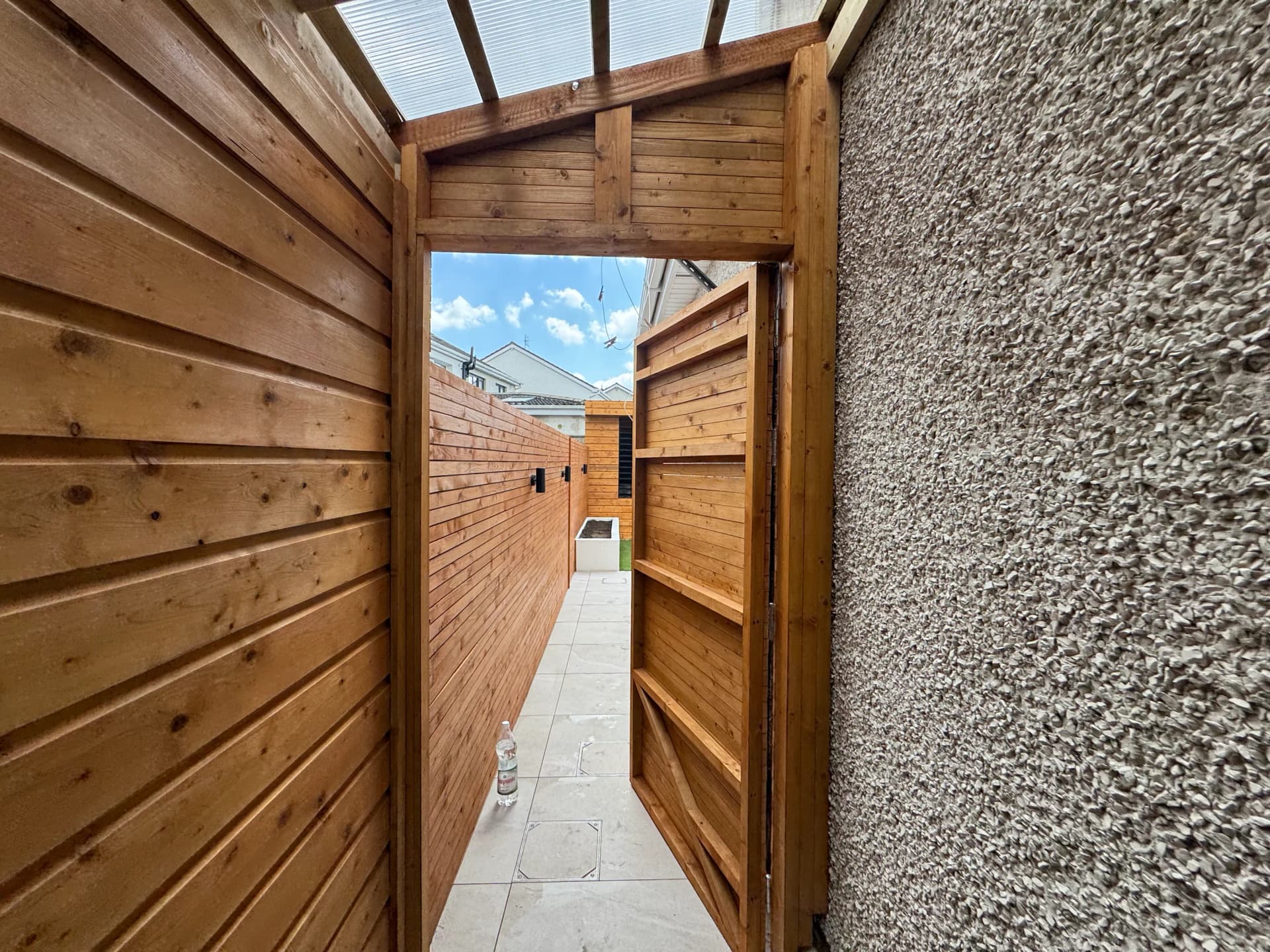 Timber slat fence with gate in a paved courtyard