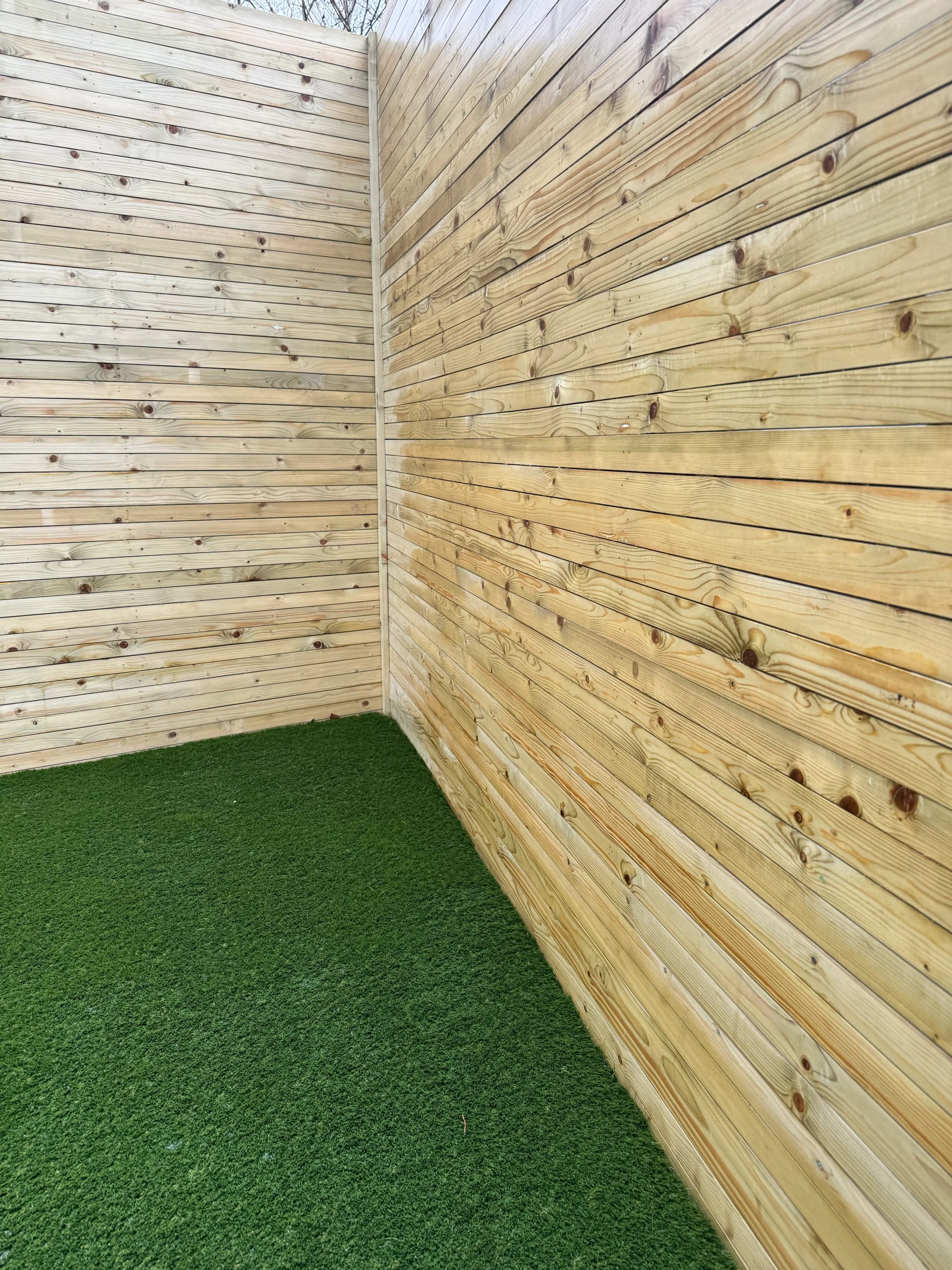 Horizontal timber fence boards in a corner with artificial lawn