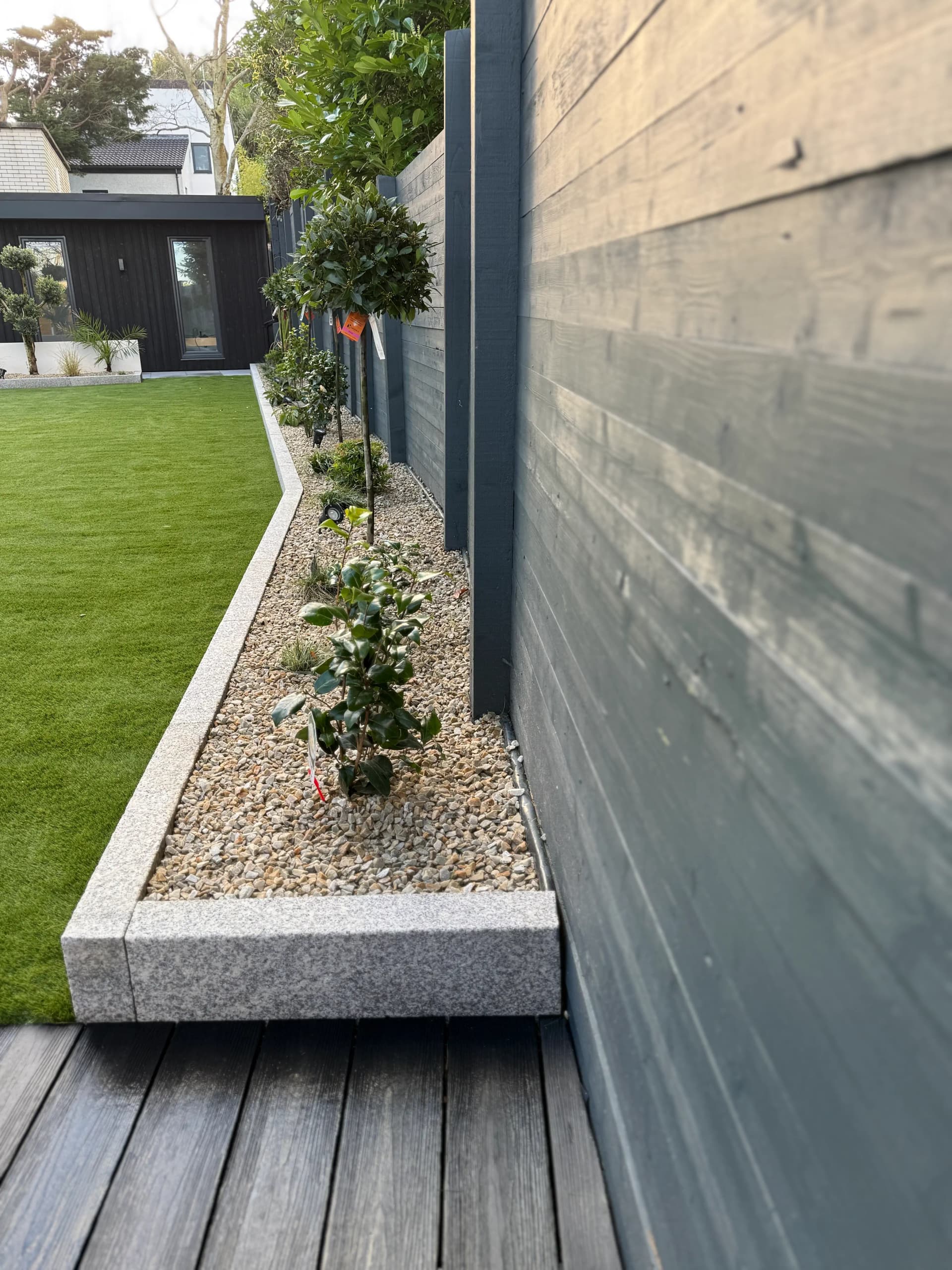Painted timber fence with uplighting and mature trees