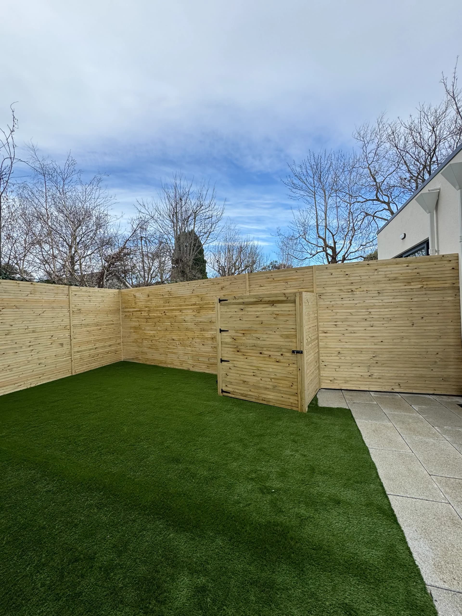 Timber fence with integrated gate and artificial grass lawn