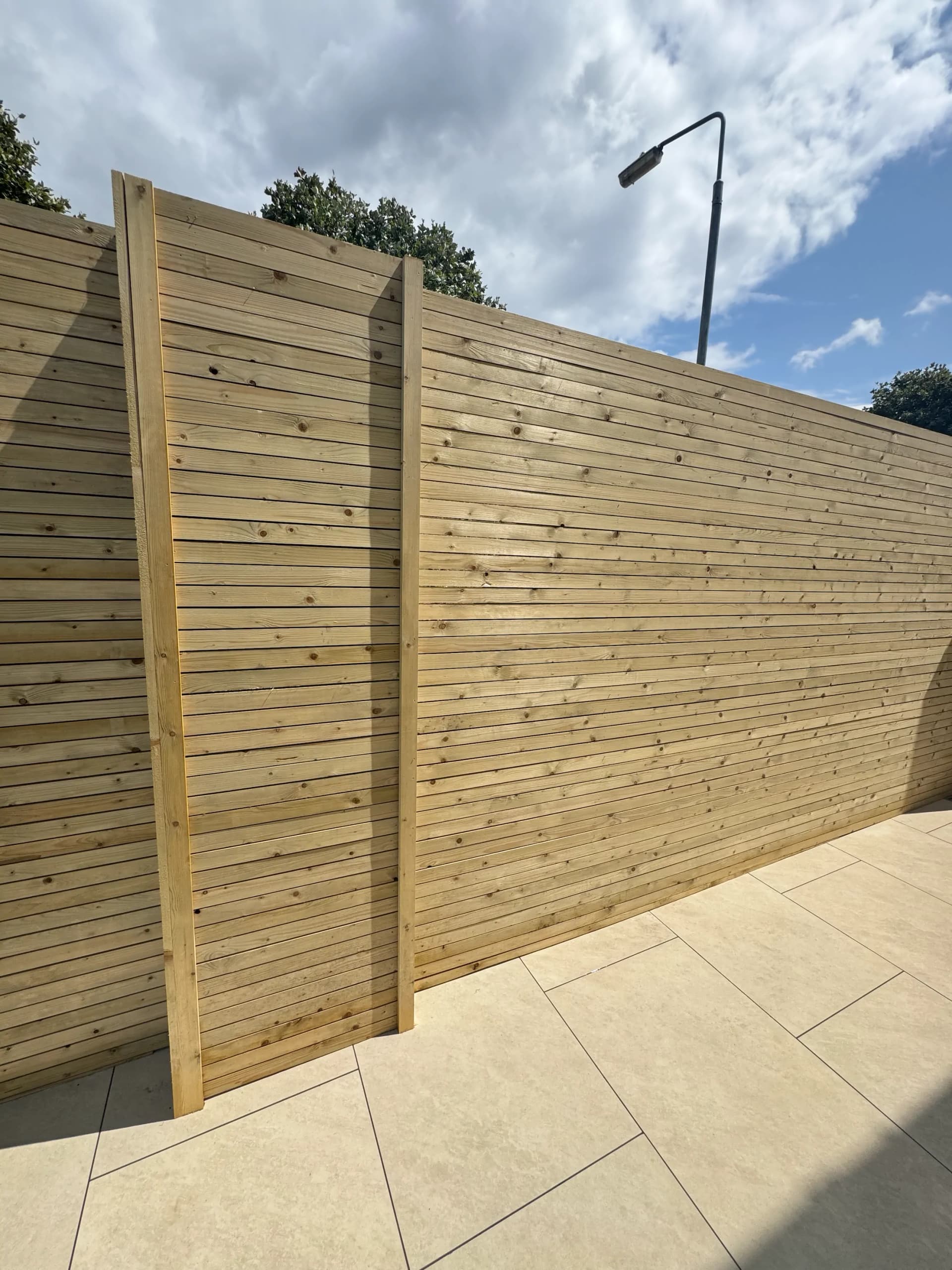 Tall timber fence panels beside a porcelain patio