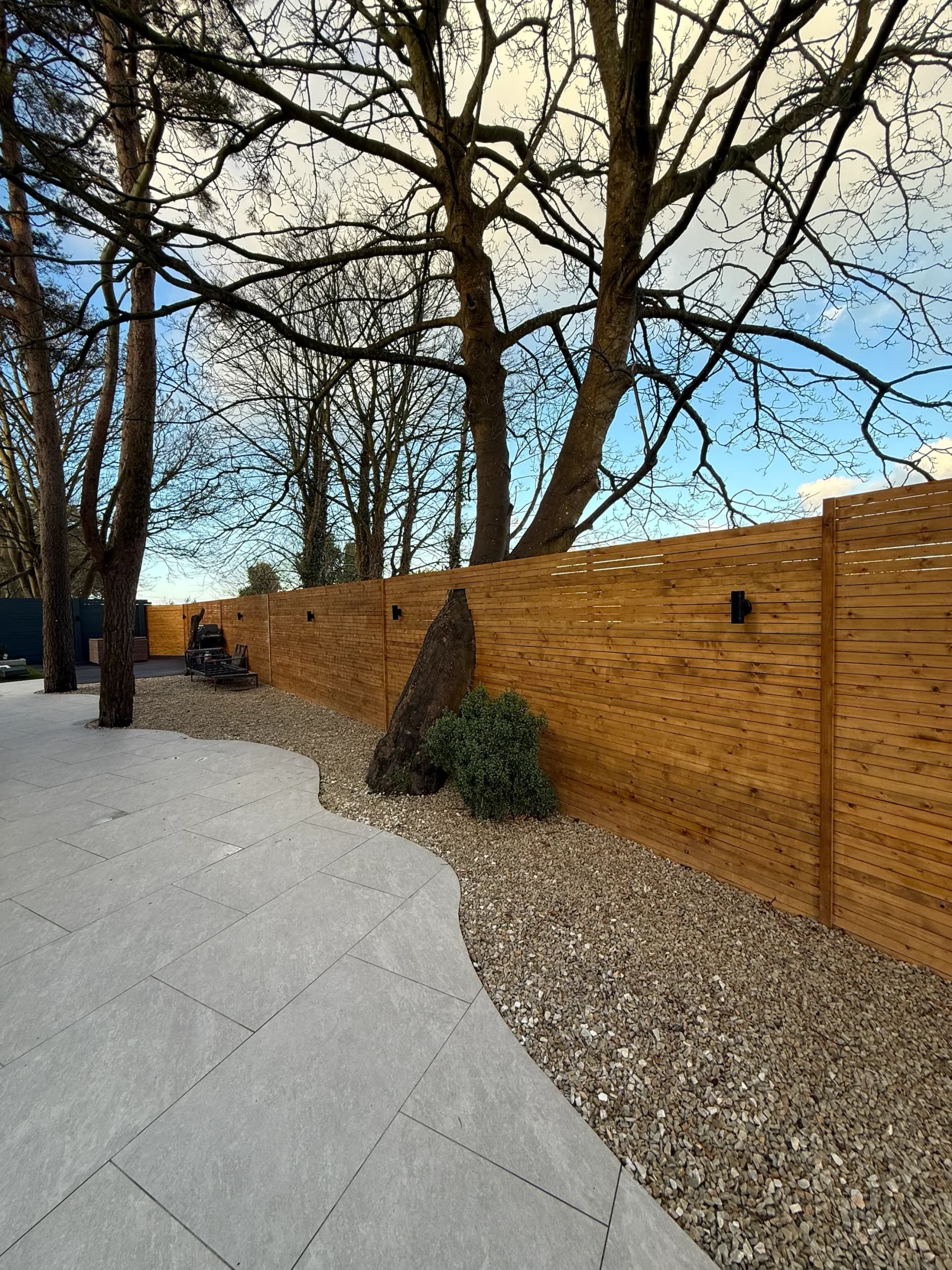 Timber slat fence with wall lights and gravel border