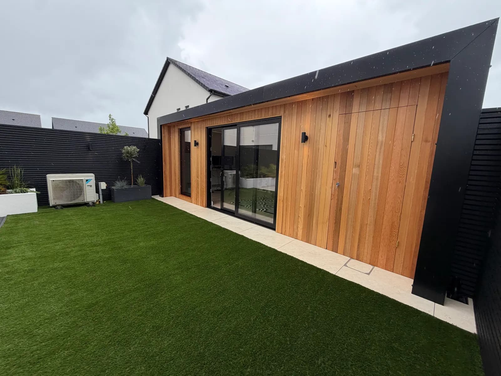 Cedar garden room with artificial grass and black slat fencing