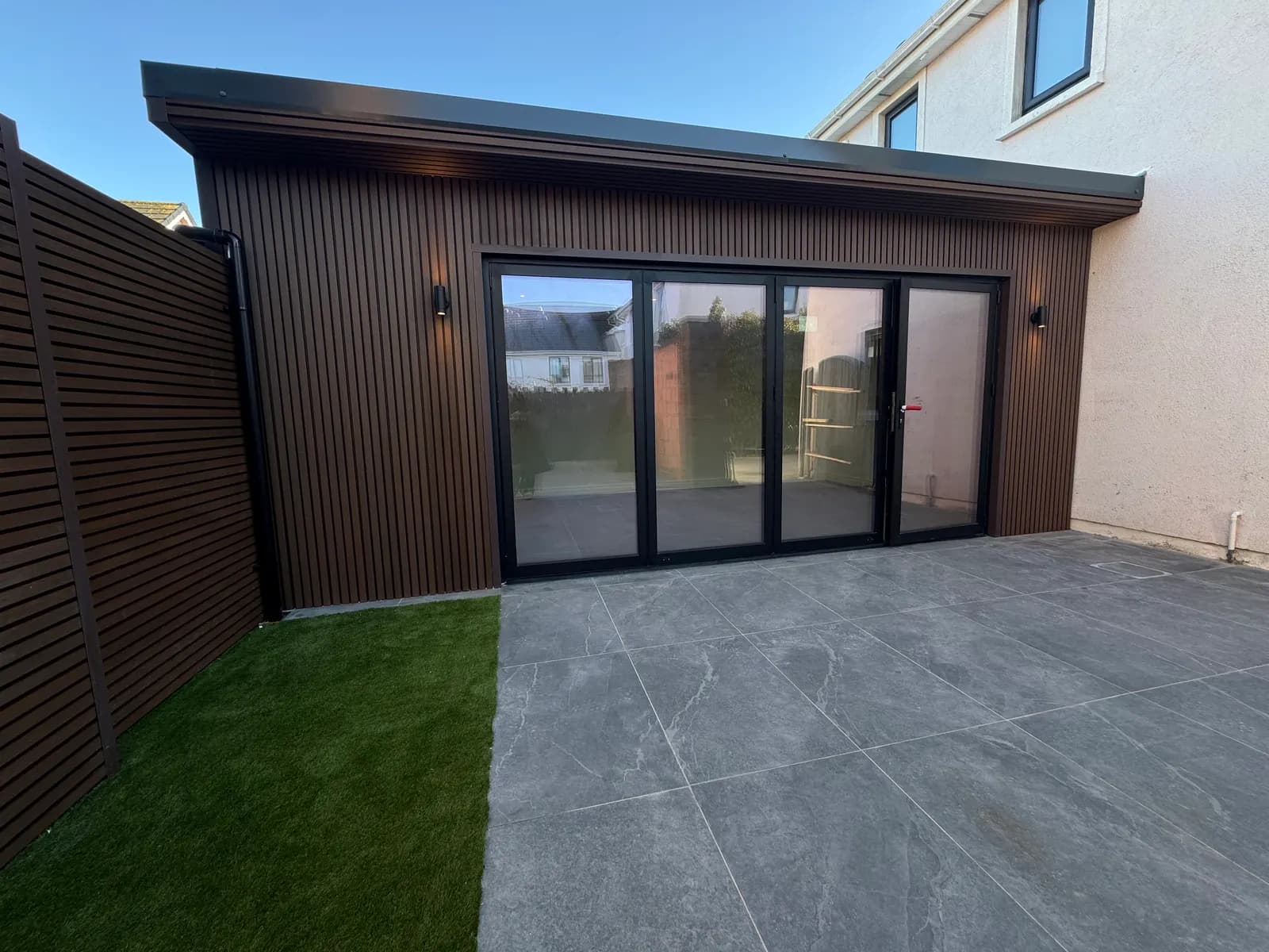 Composite clad garden room with bifold doors and porcelain patio