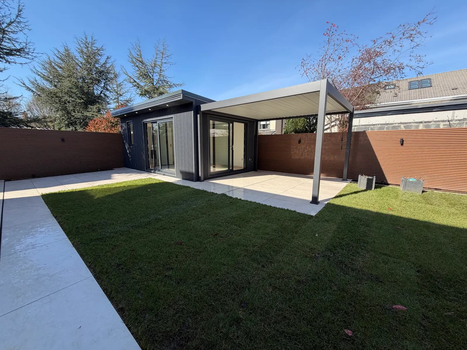 Modern garden room with aluminium pergola and lawn