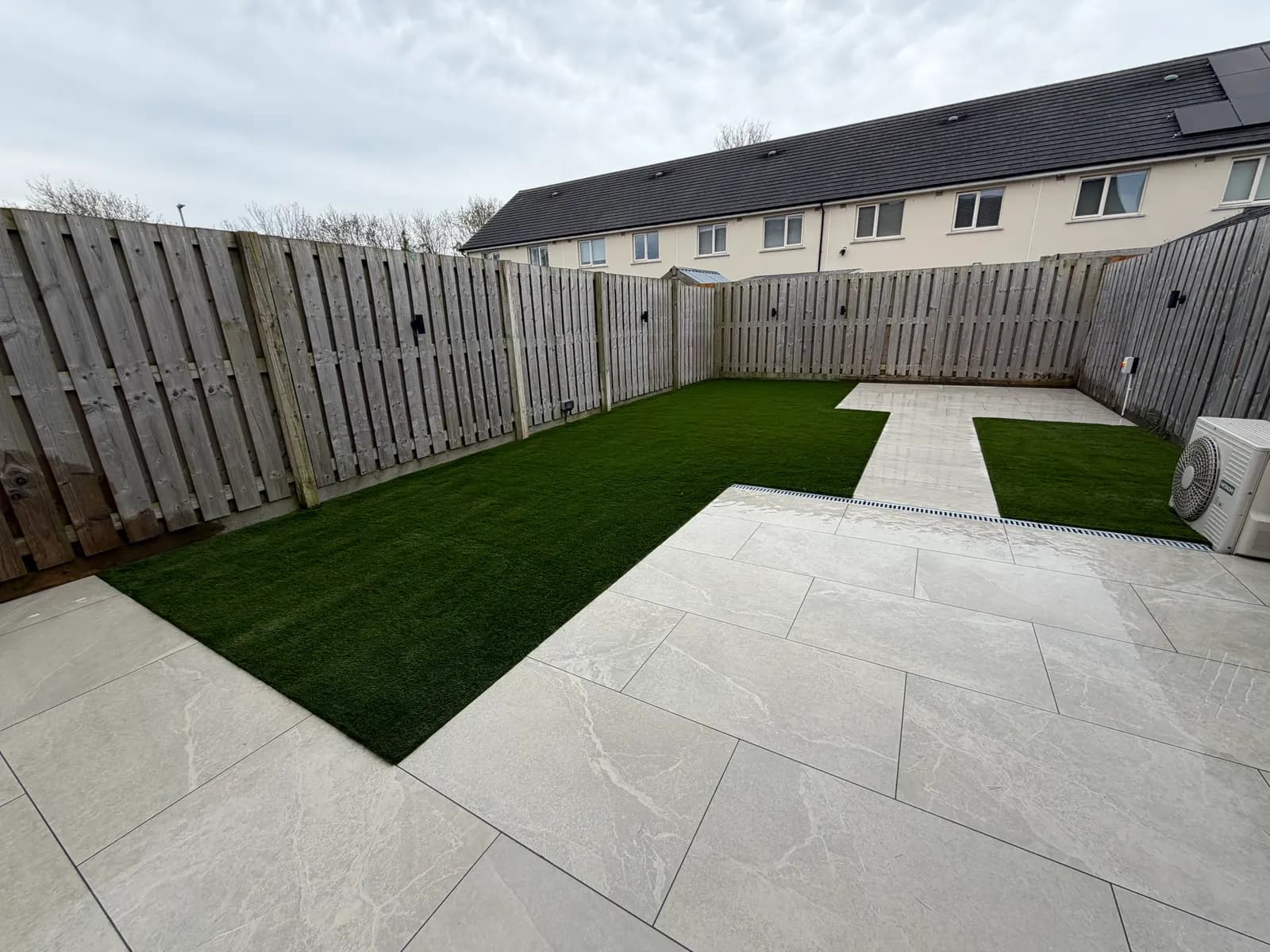 Compact back garden with porcelain paving and easy-care artificial lawn