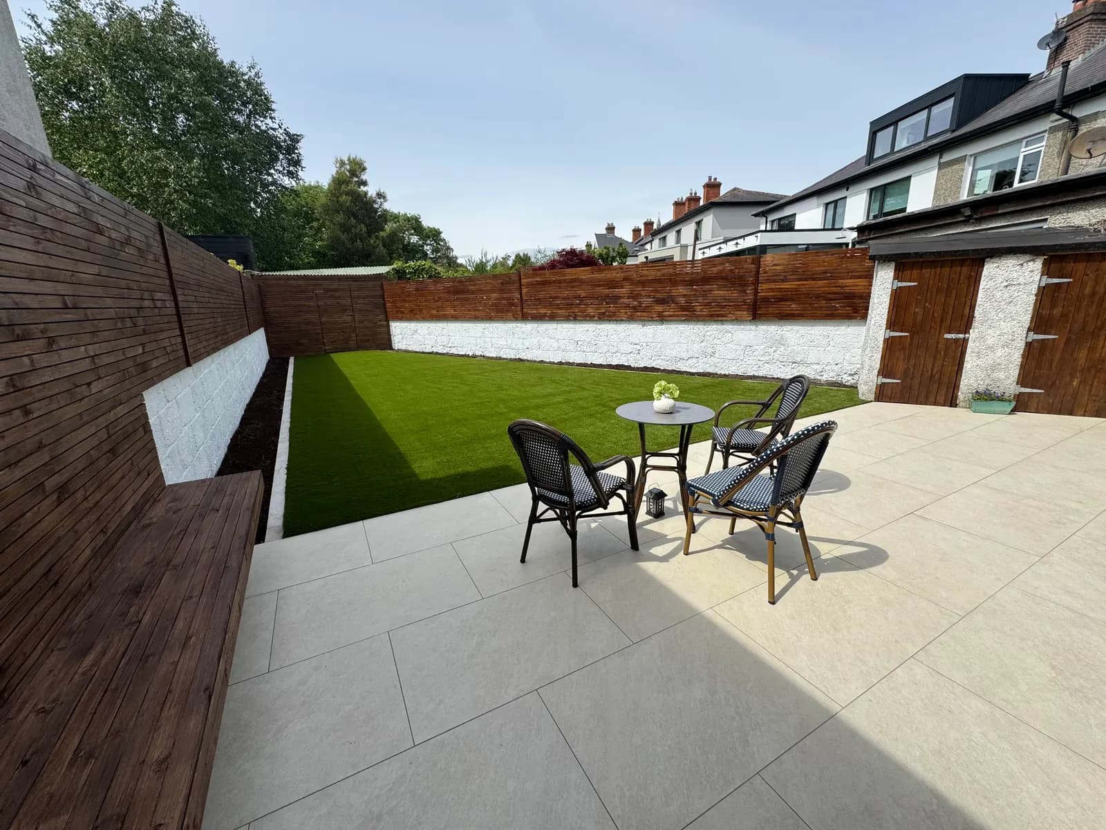 Garden seating area with porcelain patio, bench and artificial lawn