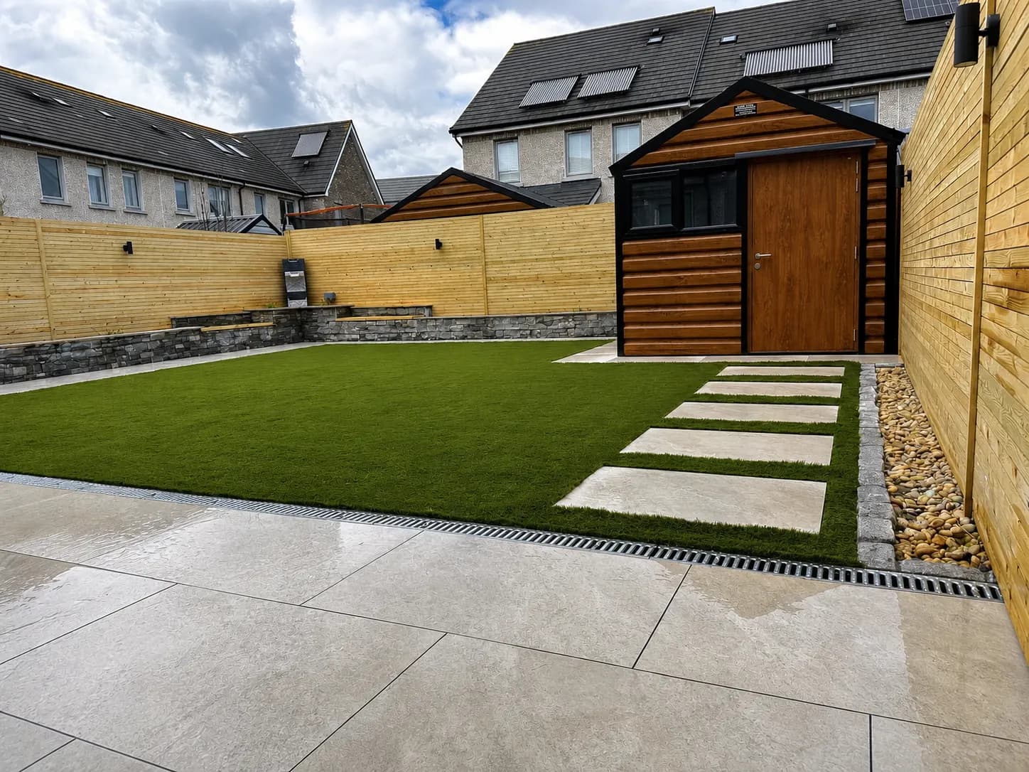 Low-maintenance garden with artificial lawn, stepping stones and garden shed