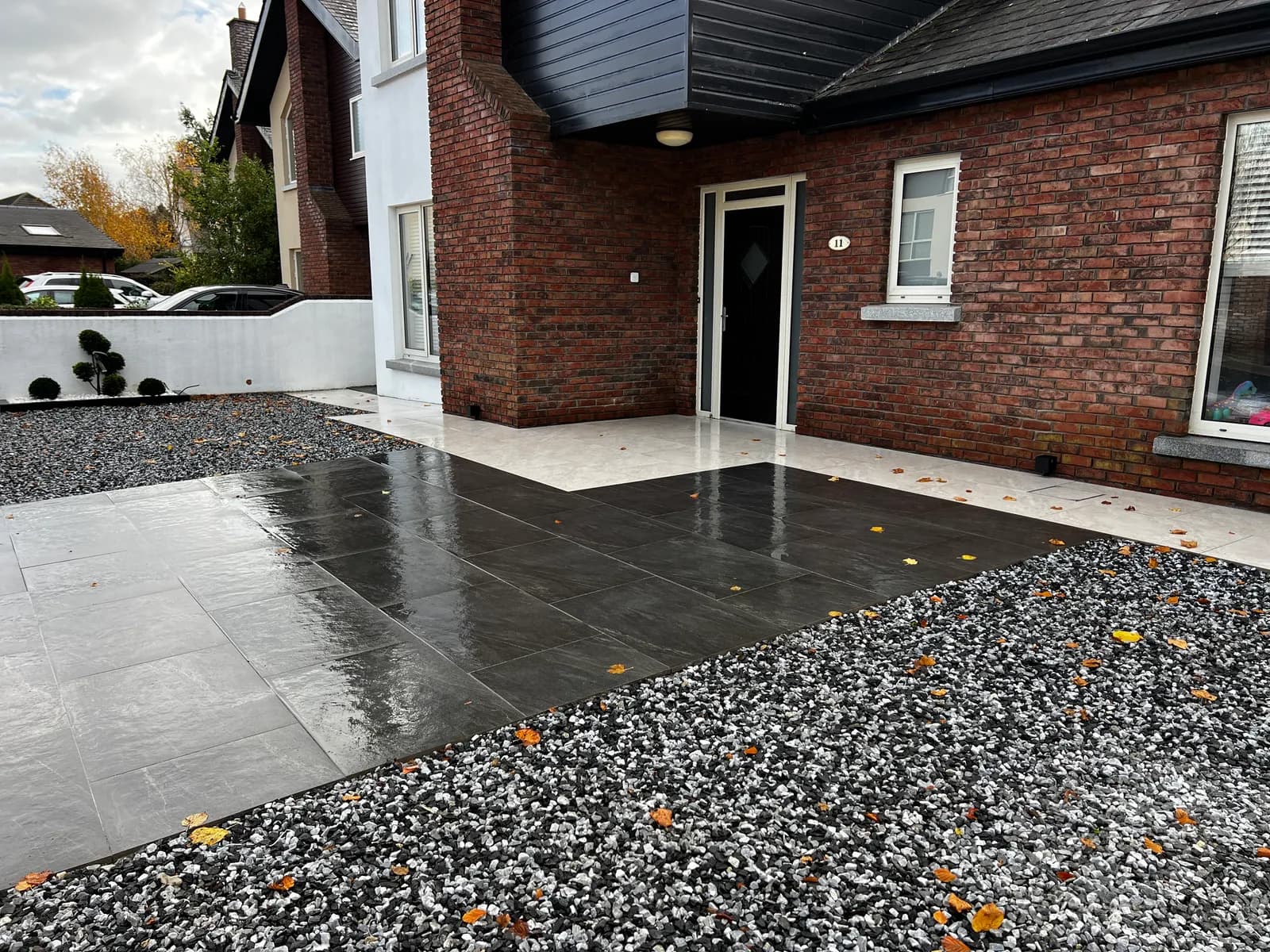 Dark porcelain driveway and entrance with decorative stone border