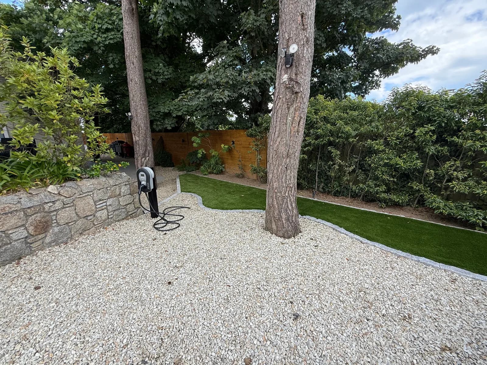 Gravel parking area with EV charger, granite kerb and artificial grass