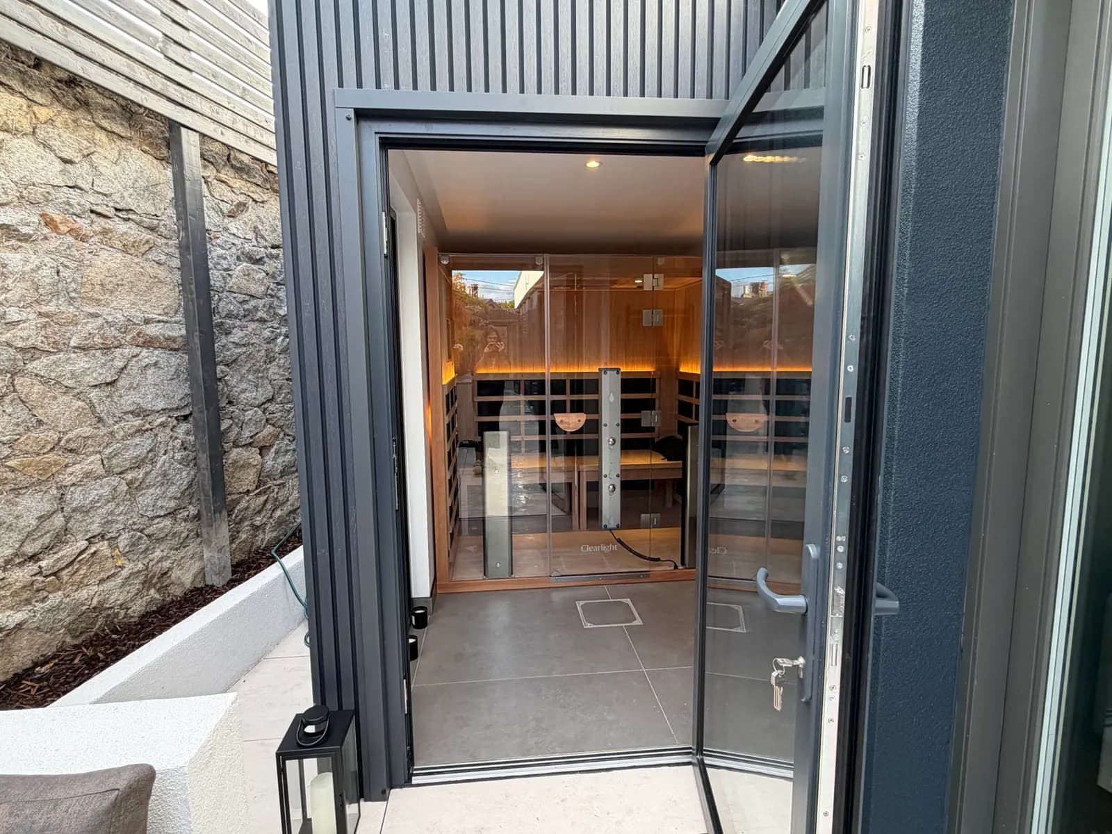Entrance to a bespoke garden wellness building with sauna visible through glass doors