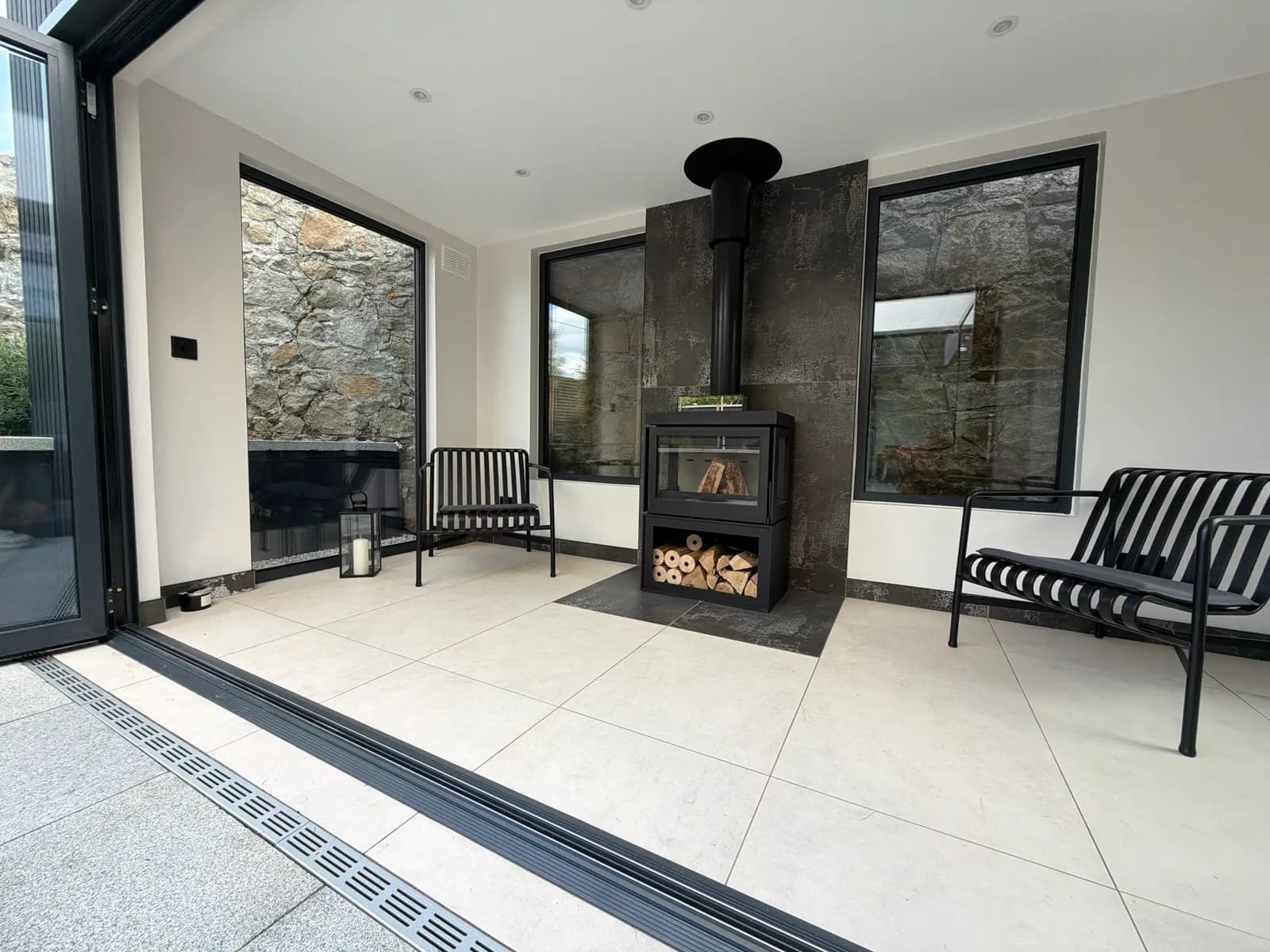 Glass room with wood burning stove and stone walls seen through the windows