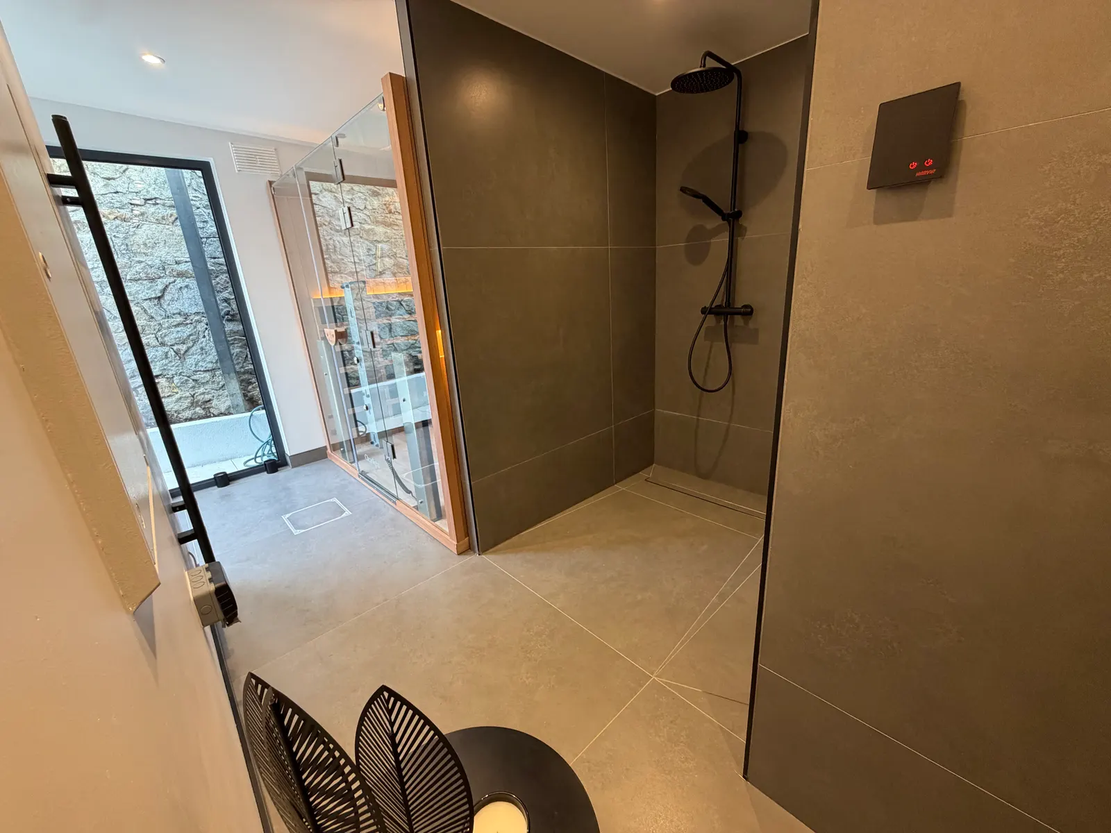 Indoor rainfall shower in a garden wellness room with view towards the sauna