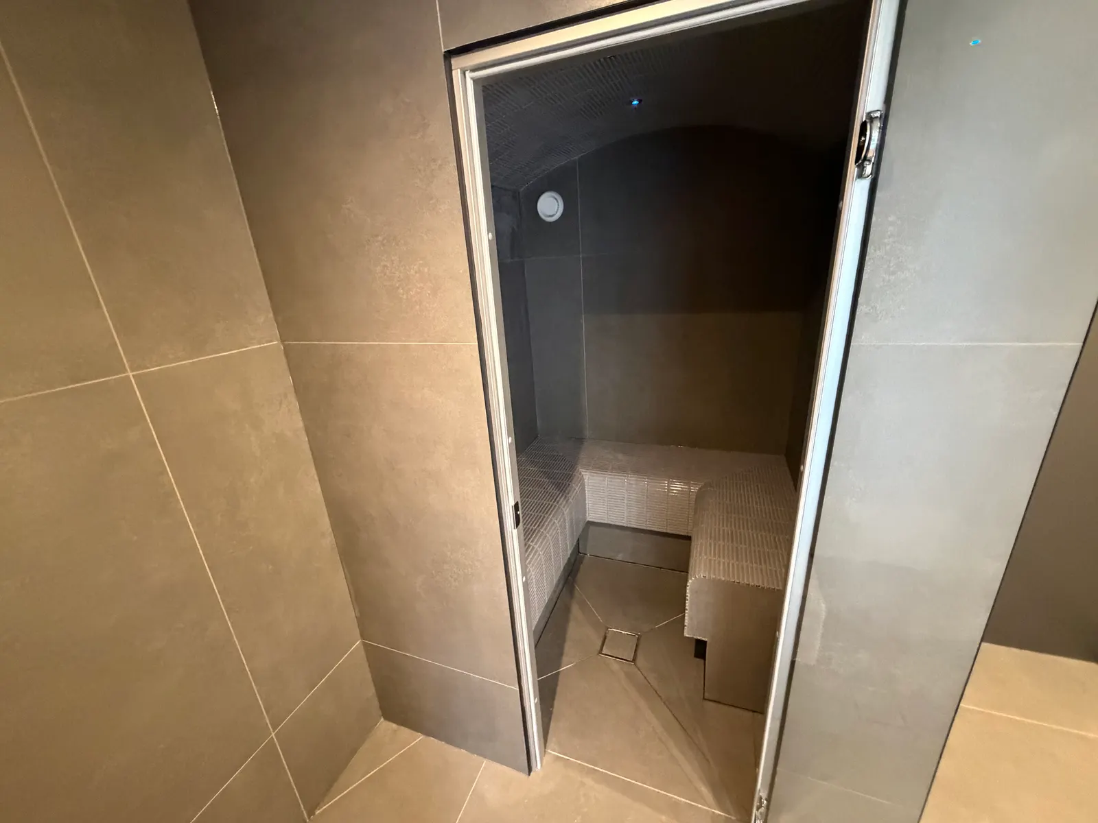 Tiled steam room interior with bench seating in a garden wellness area