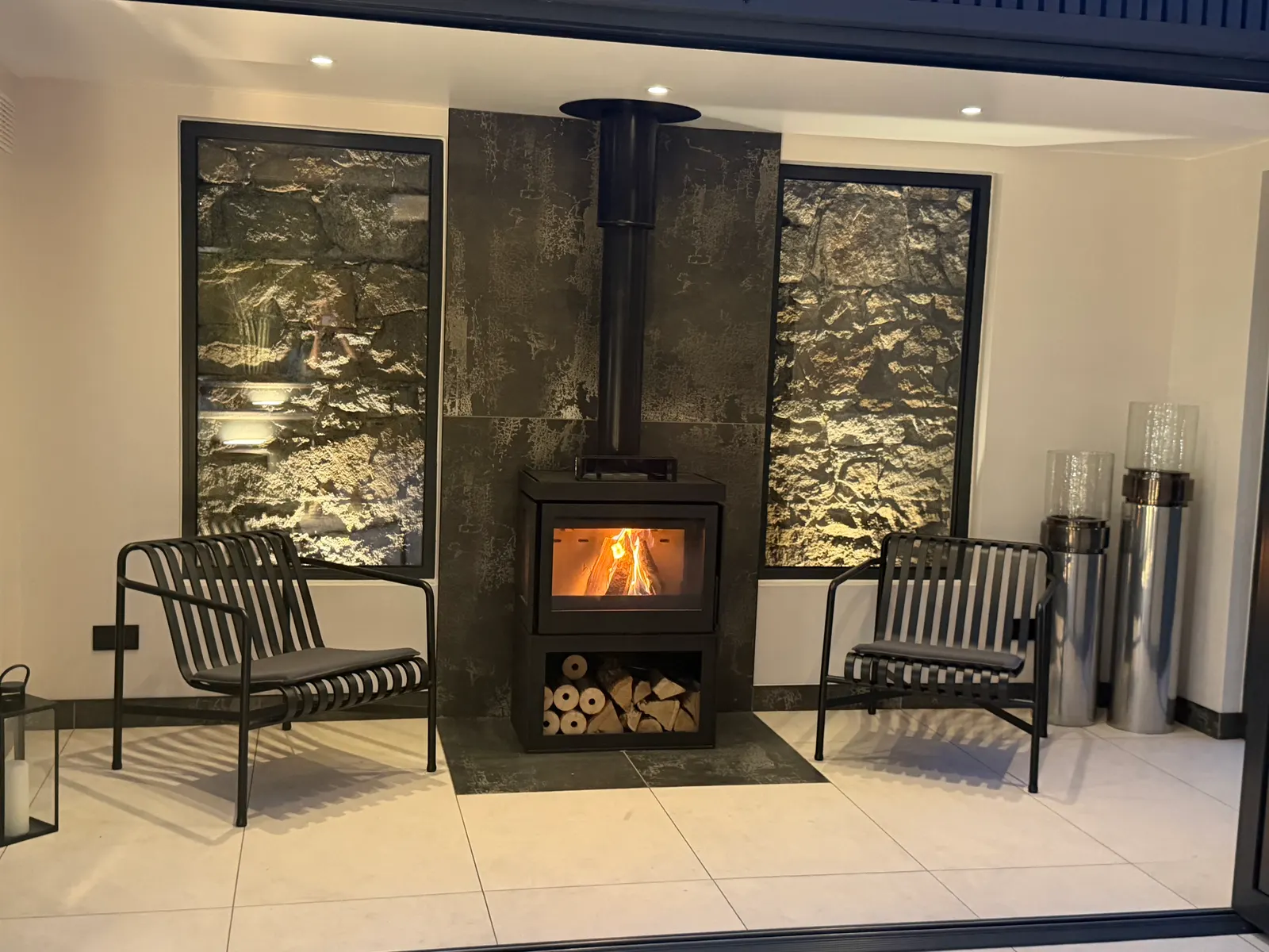 Wood burning fireplace with stone feature panels in a glass relaxation room