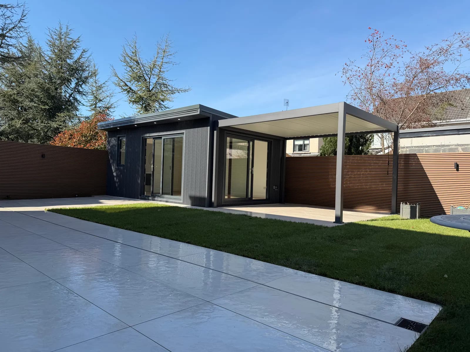 Contemporary garden room with aluminium louvre pergola and natural lawn