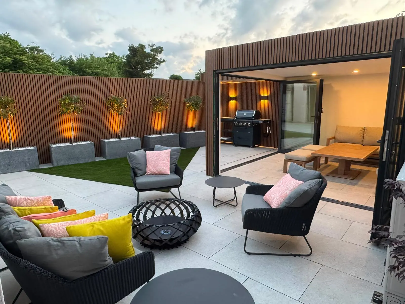 Bespoke garden lounge area with porcelain patio and lit olive trees