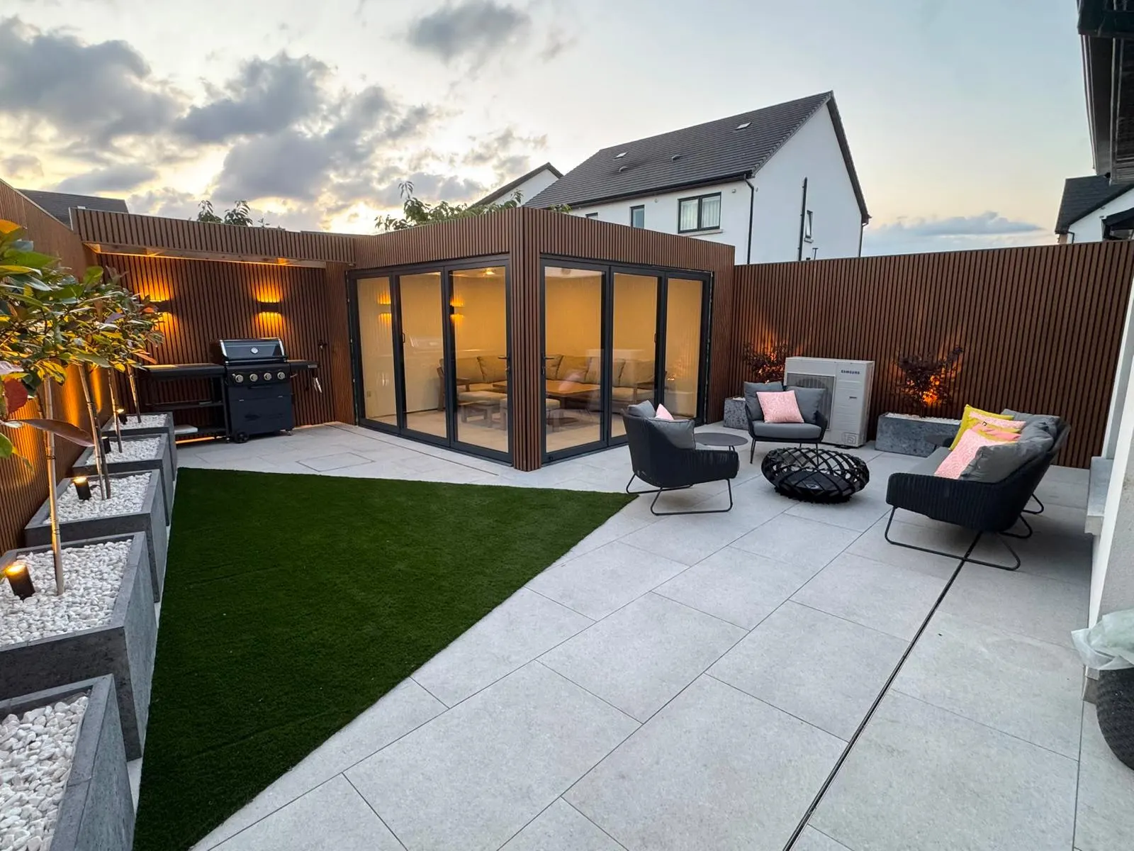 Premium garden room at dusk with outdoor lighting, fire pit and BBQ area