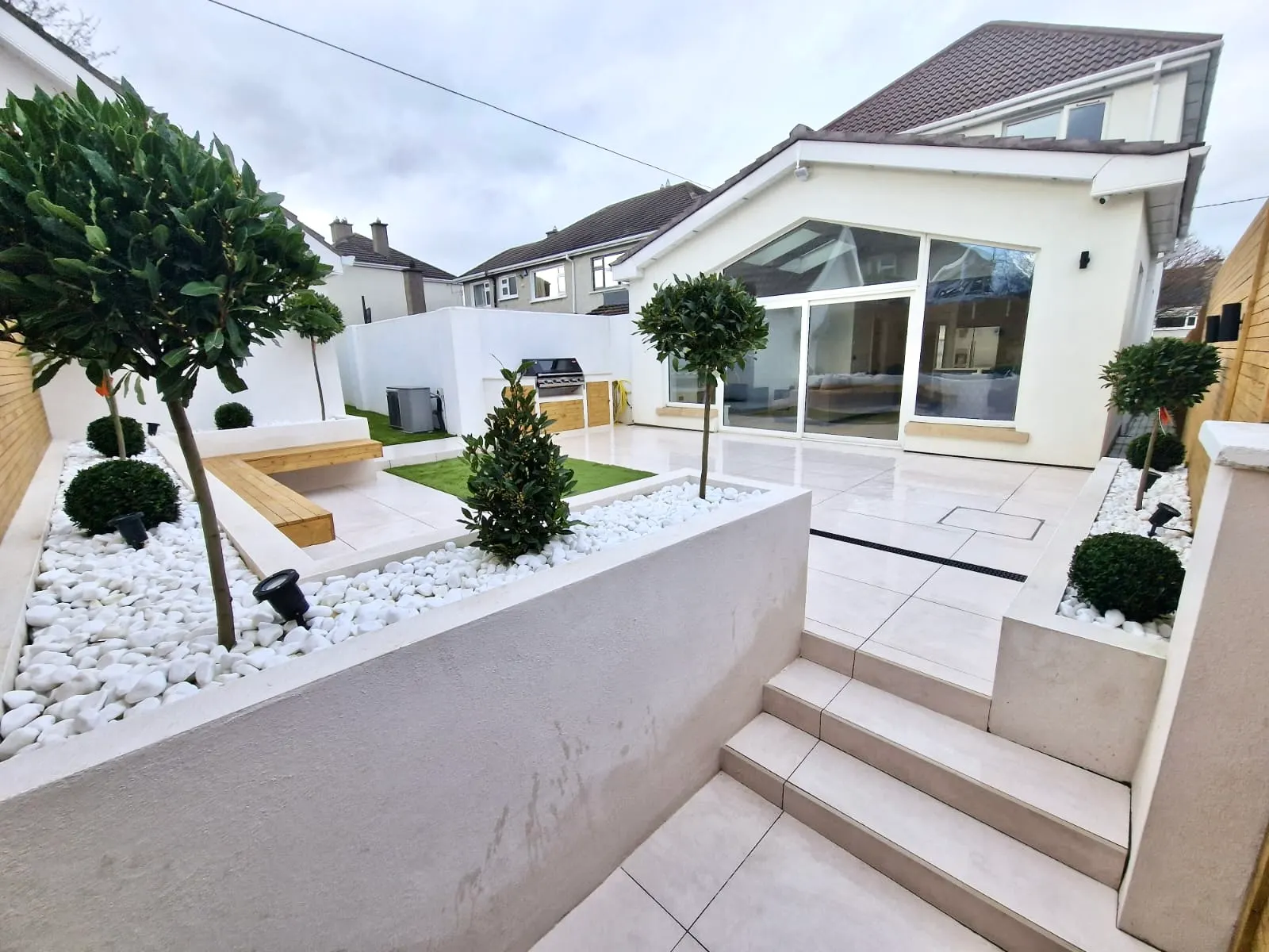 Bespoke garden with white rendered planters, bay trees and porcelain steps